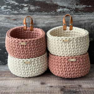 A group of stacked handmade mini baskets in natural and blush colours
