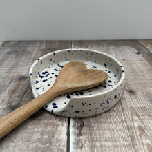 Load image into Gallery viewer, A handmade spoon rest with a splatter ware glaze holding a handmade heart shaped wooden spoon