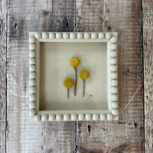 Decorative bobbin frame with yellow flowers sat on a wooden surface