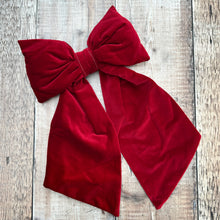 Load image into Gallery viewer, A large handmade bow in claret red velvet on a brown wooden table
