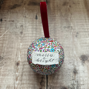 A Liberty covered bauble with burgundy velvet ribbon and a calligraphy message of Merry & Bright