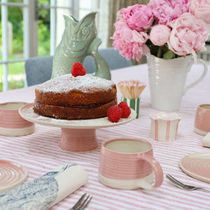 A country table laid with perfectly sized cake plates and cake stand and mugs