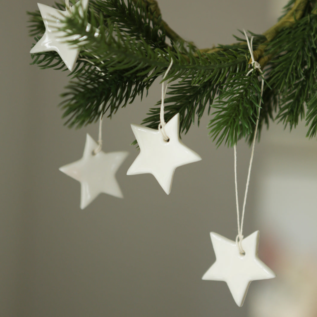 Handmade porcelain stars hanging from the branch of a christmas tree