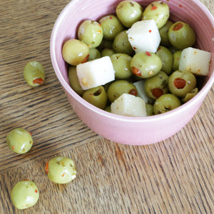 A handmade Barton Croft bowl full of olives and manchego in their distinct Rhubarb glaze