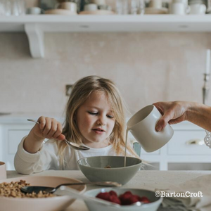 A little girl eating cereal and using the Dimpled Jug in Milk Glaze by Barton Croft