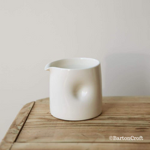 Load image into Gallery viewer, Handmade Dimpled Jug by Barton Croft in a Milk Glaze, sat atop a wooden stool