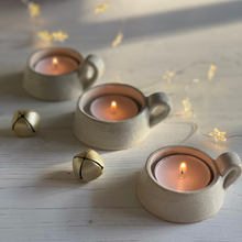 Load image into Gallery viewer, A trio of rustic handled tealight holders with speckled glaze on a christmas table decorated with fairy lights and bells