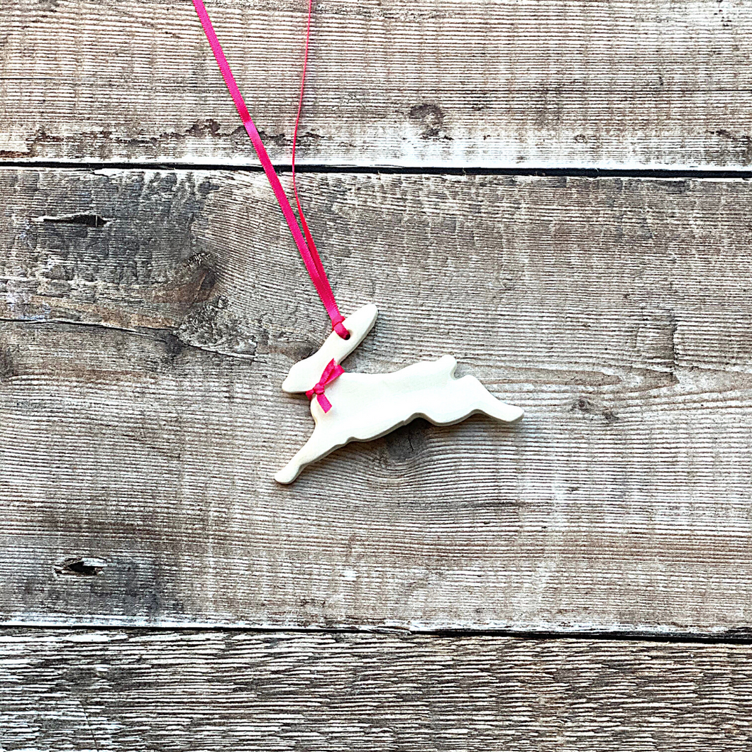 a handmade ceramic running hare easter decoration with satin pink ribbon